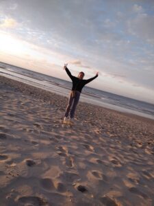 Hélène die springt in de lucht op het strand, tekstschrijver geniet van vrijheid